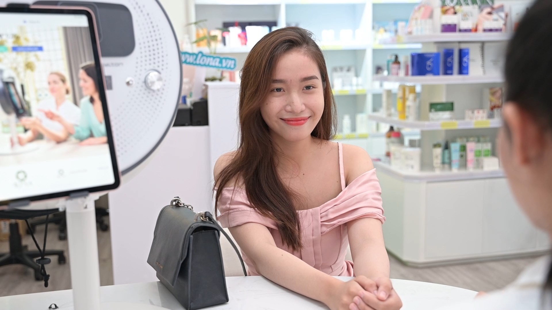 Khách ngồi bên máy soi da OBSERV tại khu tư vấn, phía sau là kệ sản phẩm — Lona Home Spa, Cần Thơ