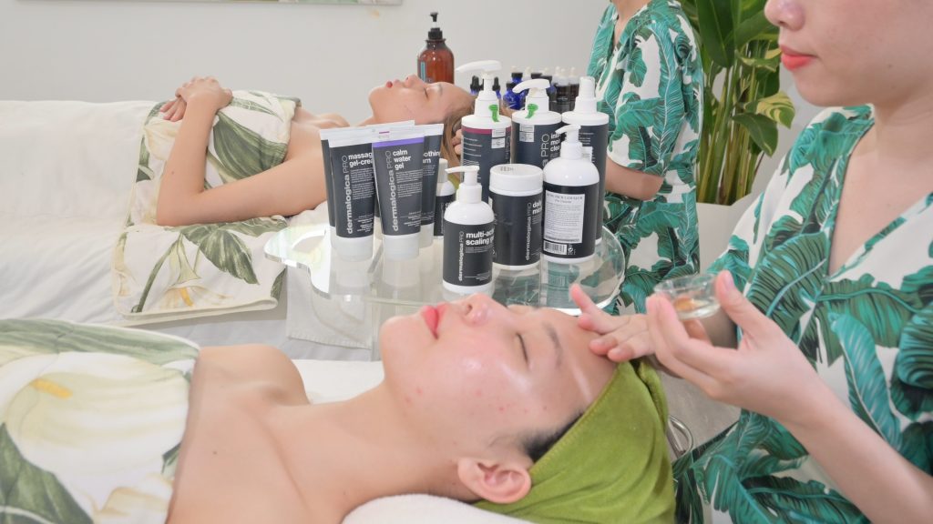 Dãy lọ sản phẩm chuyên dụng xếp trên kệ trong phòng trị liệu — Lona Home Spa, Cần Thơ